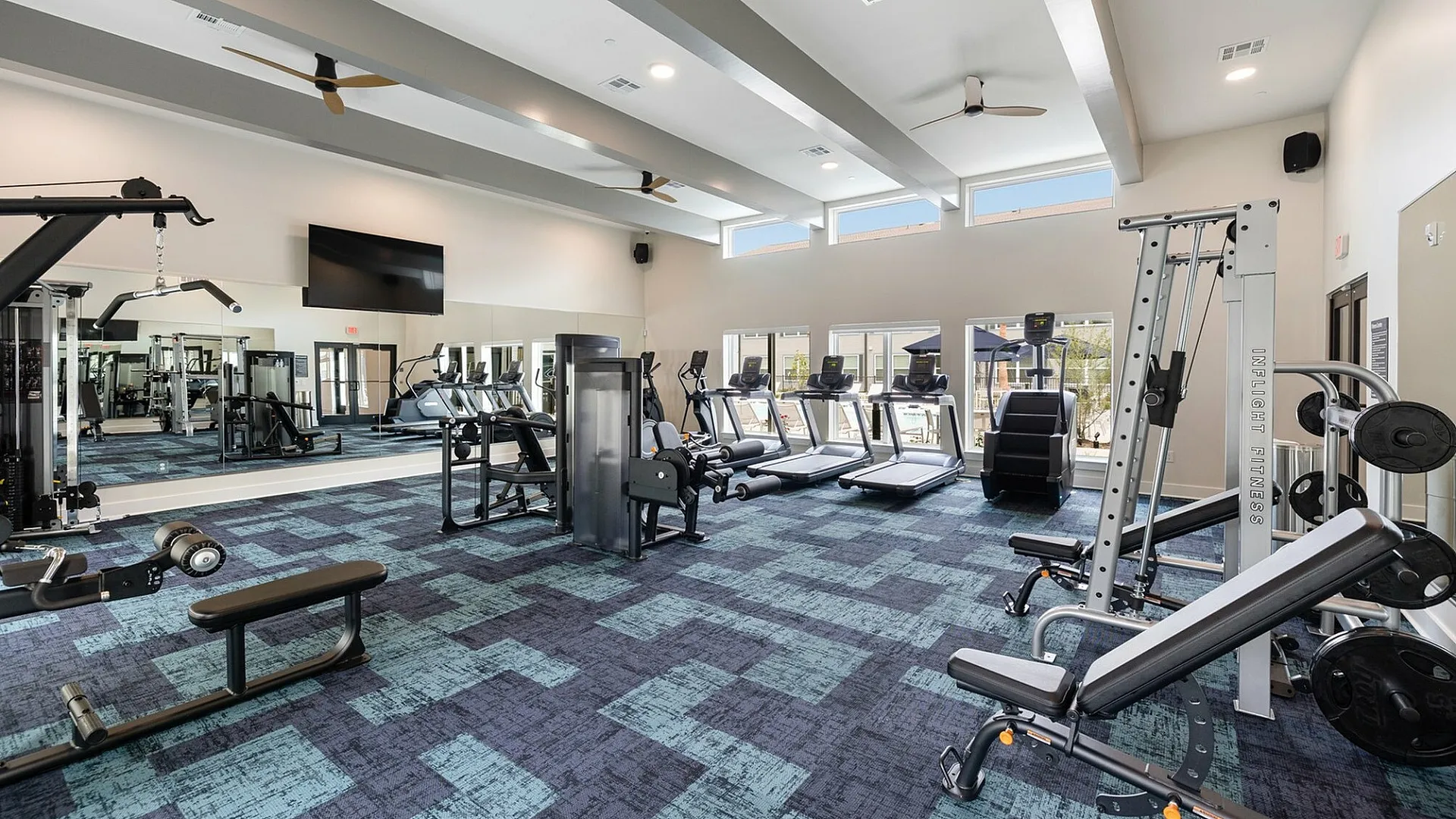 Bright and modern fitness center featuring state-of-the-art gym equipment and large windows for natural light.