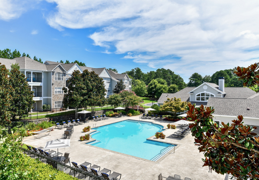 Luxurious apartment complex with a stunning outdoor pool, surrounded by lush greenery and elegant buildings, offering a resort-style living experience.