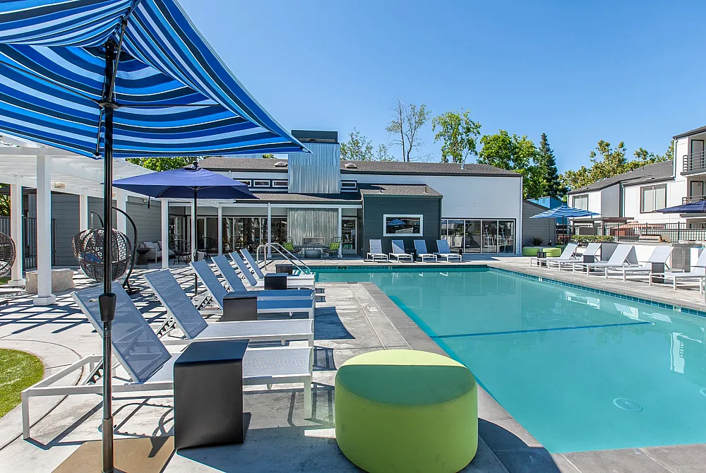 Luxurious outdoor pool area with modern lounge chairs and vibrant umbrellas, perfect for relaxation under the sun.