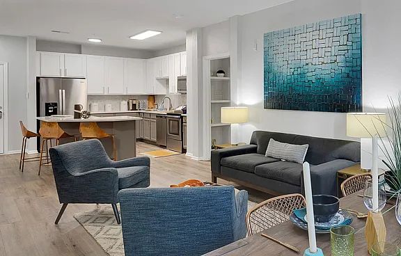 Modern open-plan living and dining area with sophisticated decor, adjacent to a sleek kitchen with stainless steel appliances and stylish bar stools.