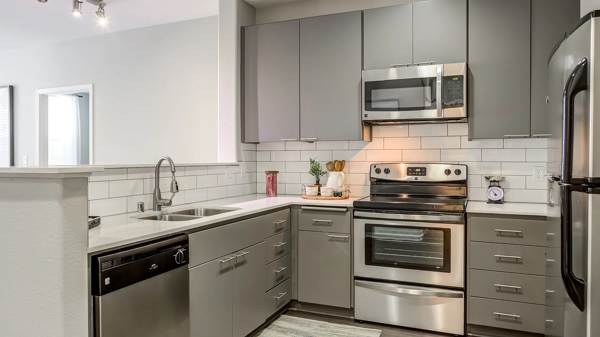 Modern kitchen with sleek gray cabinets, stainless steel appliances, and elegant subway tile backsplash.