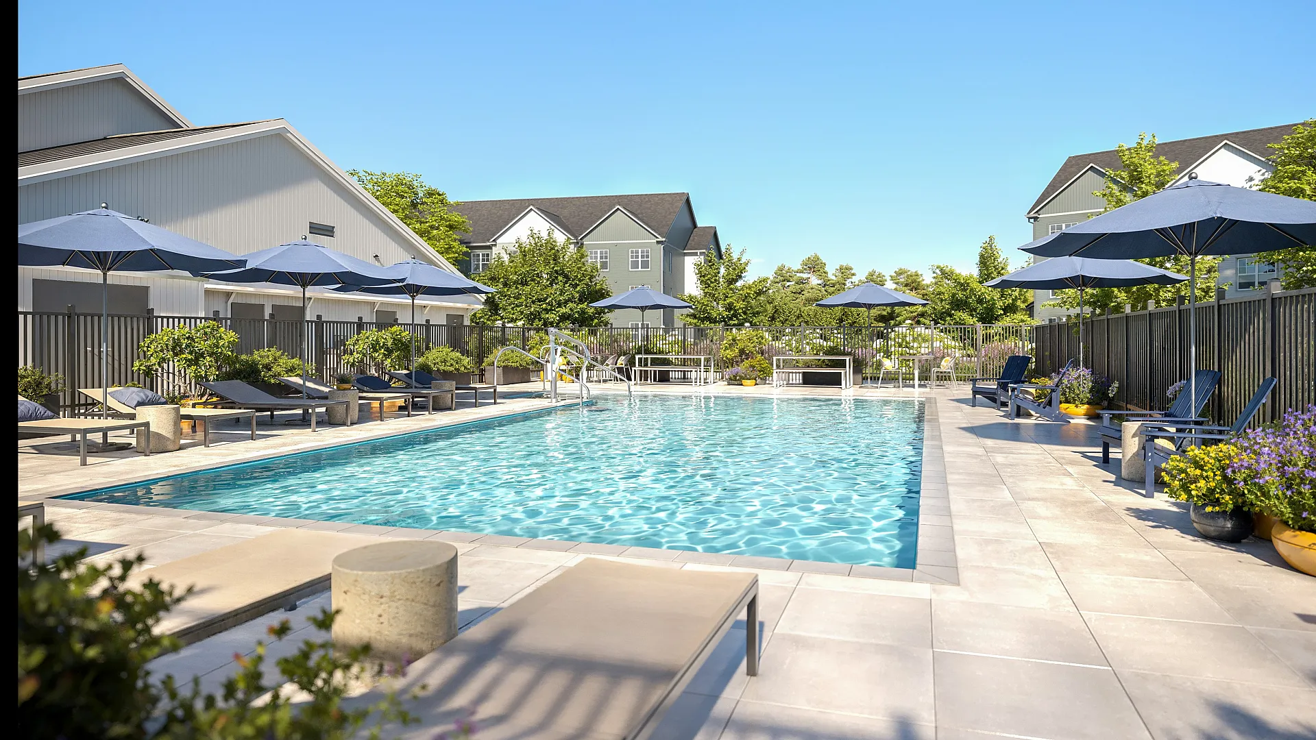 Inviting outdoor pool with sun loungers and blue umbrellas, surrounded by lush landscaping for a relaxing escape.