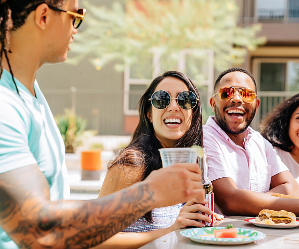 Vibrant gathering of friends enjoying outdoor dining in a stylish apartment complex, highlighting community and leisure.