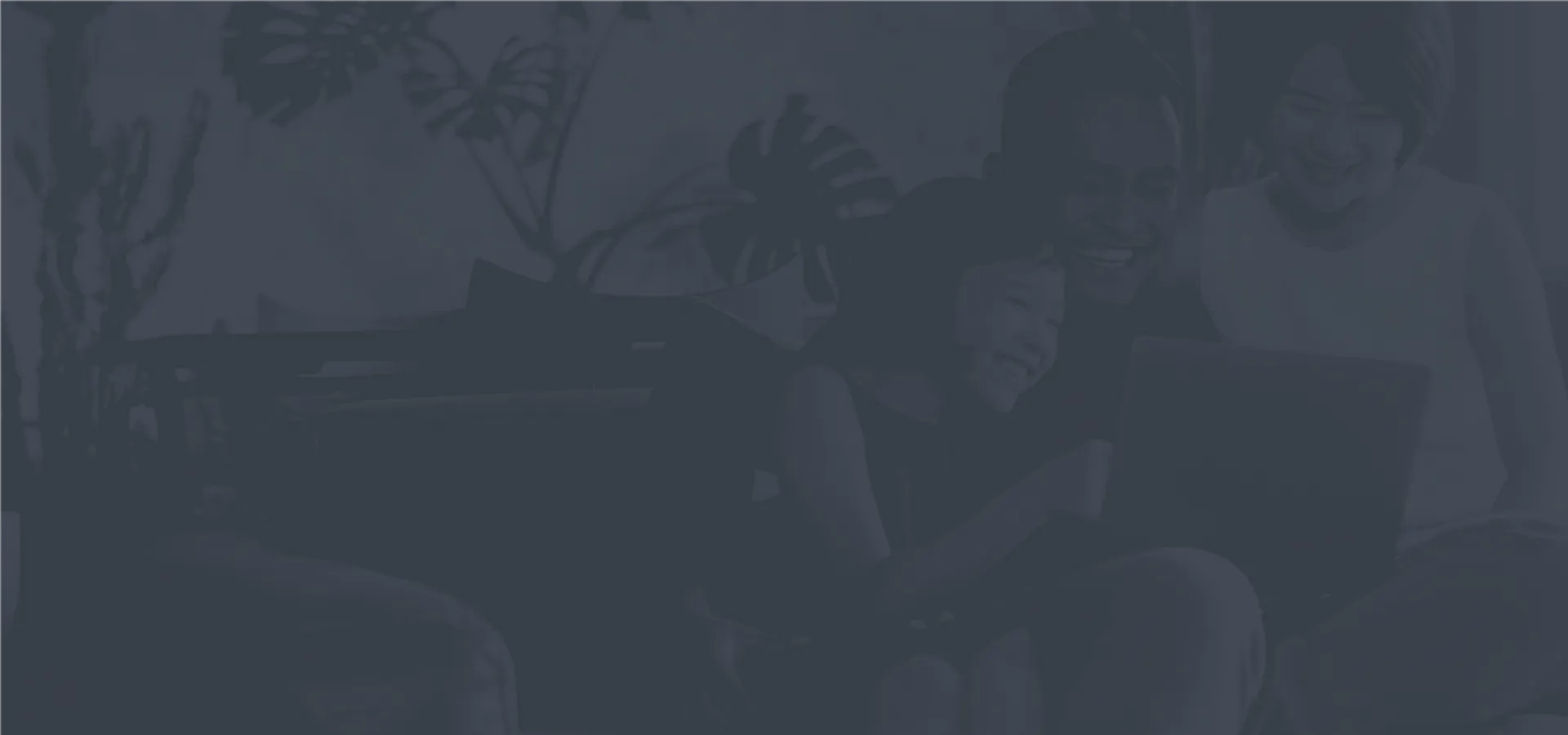 Happy family enjoying quality time together on the couch, sharing smiles and laughter while looking at a laptop in a cozy living room.