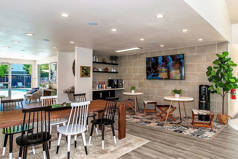 Inviting communal space with modern decor, ample seating, and a view of the outdoor pool through large glass doors.