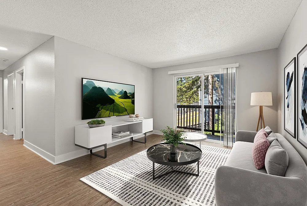Bright and inviting living room with modern furnishings, featuring a sleek flat-screen TV, elegant coffee table, and large sliding glass doors opening to a scenic balcony.