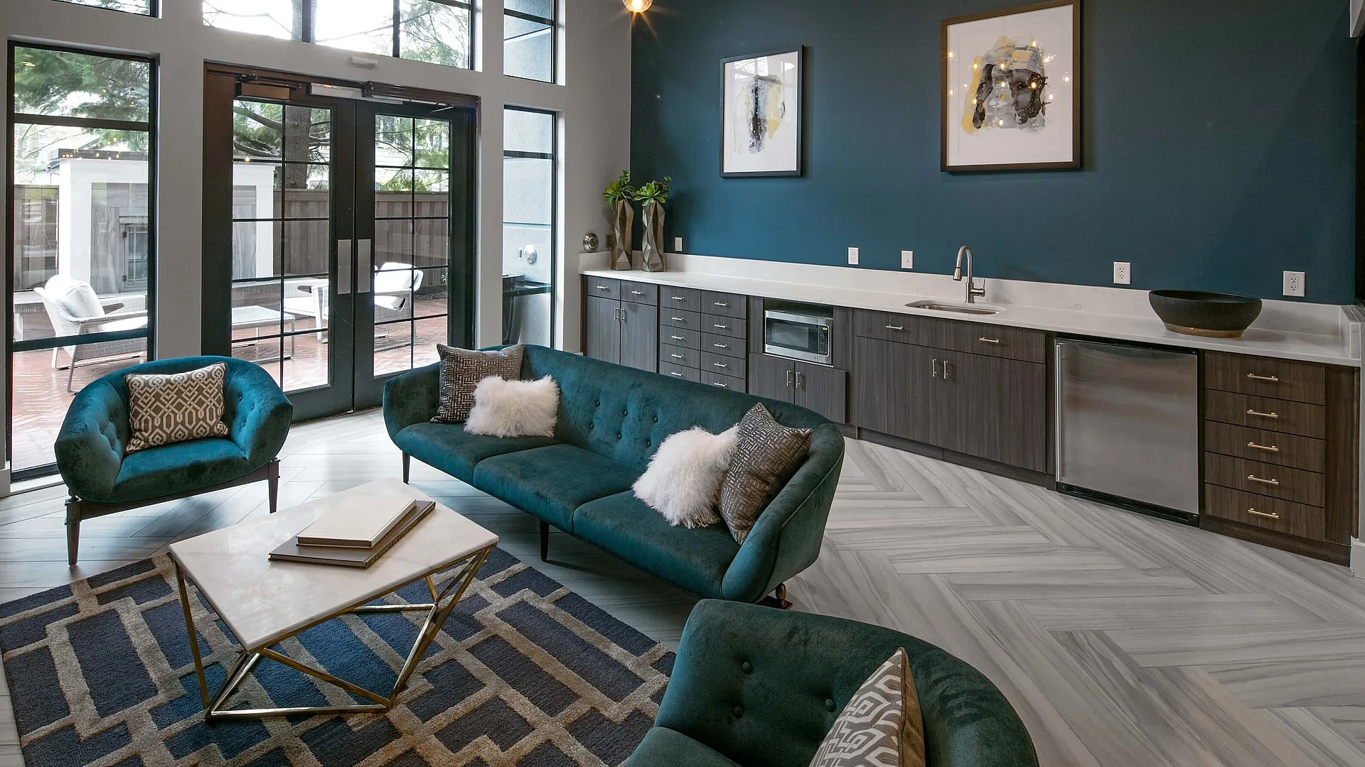 Elegant open-concept living area with chic navy accents, stylish furniture, and large windows leading to a private patio.