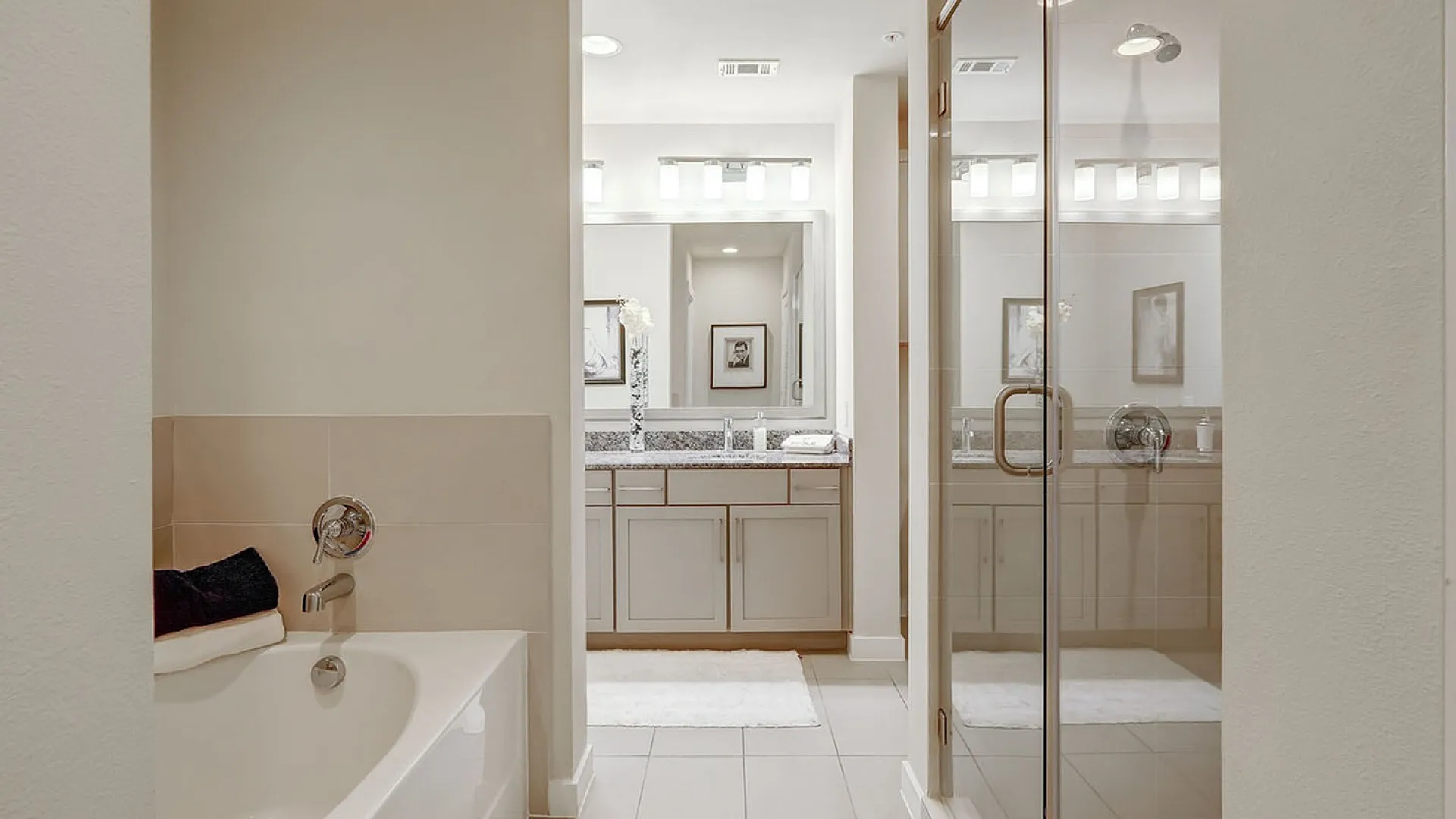 Elegant bathroom featuring a luxurious bathtub, modern glass shower, and sleek double vanity with ample lighting.