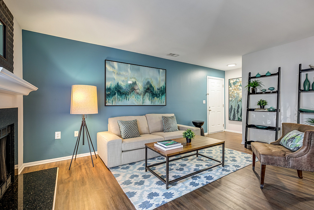 Charming living room with blue accent wall, cozy beige sofa, and stylish decor featuring warm lighting and elegant artwork.