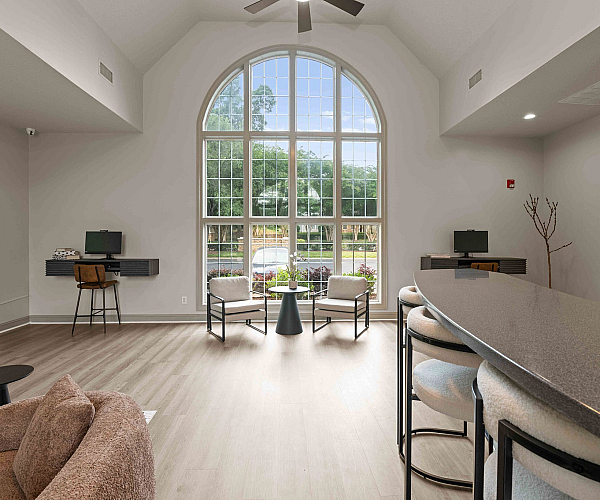 Bright, open living space with vaulted ceiling, large arched window, polished wood floors, and a sleek breakfast bar with modern seating.