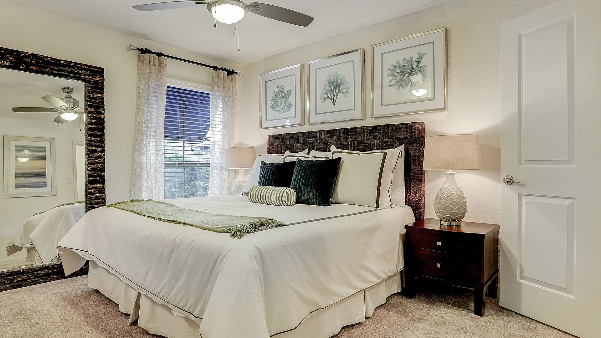 Elegant bedroom showcasing a cozy double bed with chic green accents, modern ceiling fan, and stylish decor, creating a serene retreat.