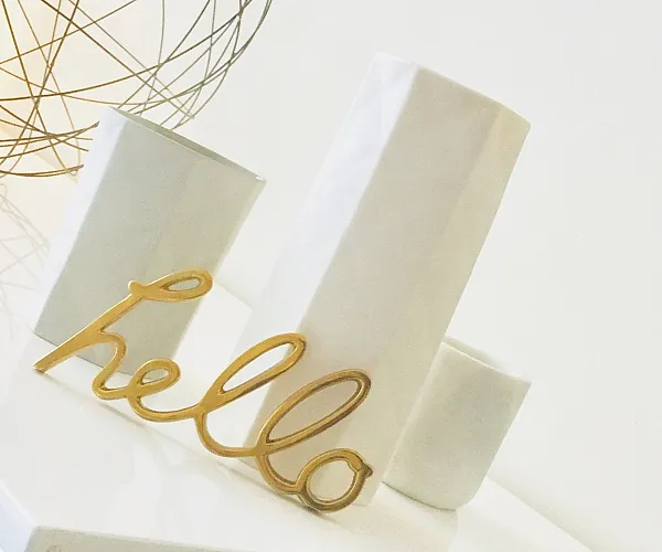 Chic interior decor with a modern geometric lamp, elegant white vases, and a golden 'hello' sign.