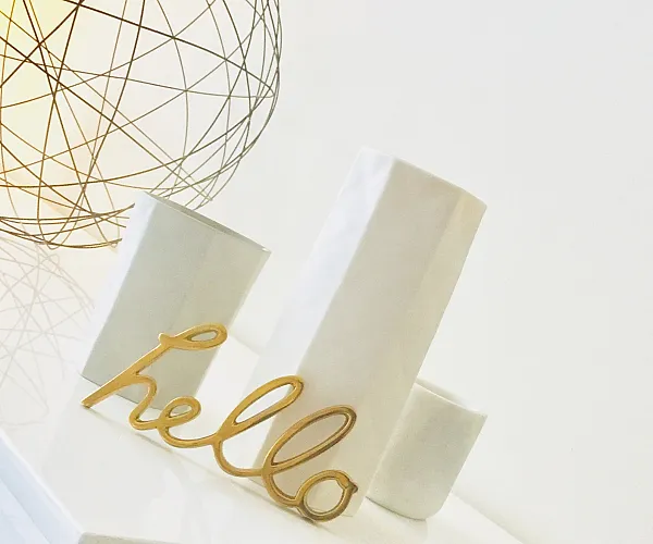 Chic interior detail showcasing a sleek modern table adorned with elegant decor, including a golden 'hello' sign and minimalist ceramics.