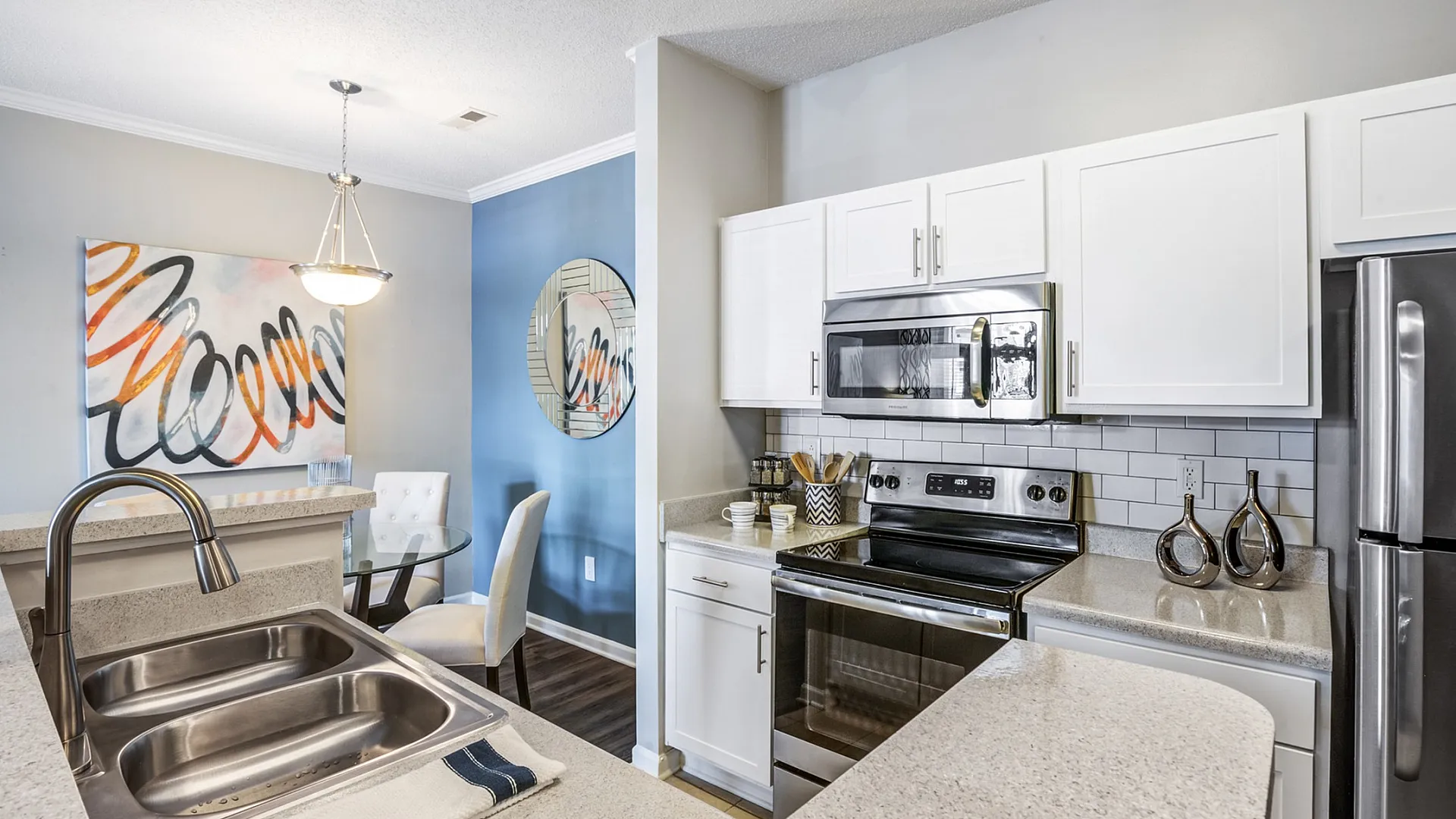 Modern kitchen with sleek stainless steel appliances, elegant countertops, and chic dining area featuring contemporary art.