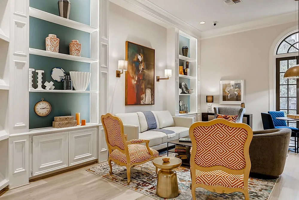 Elegant living room with built-in shelves, vibrant chairs, cozy seating, and a stylish dining area by arched windows.