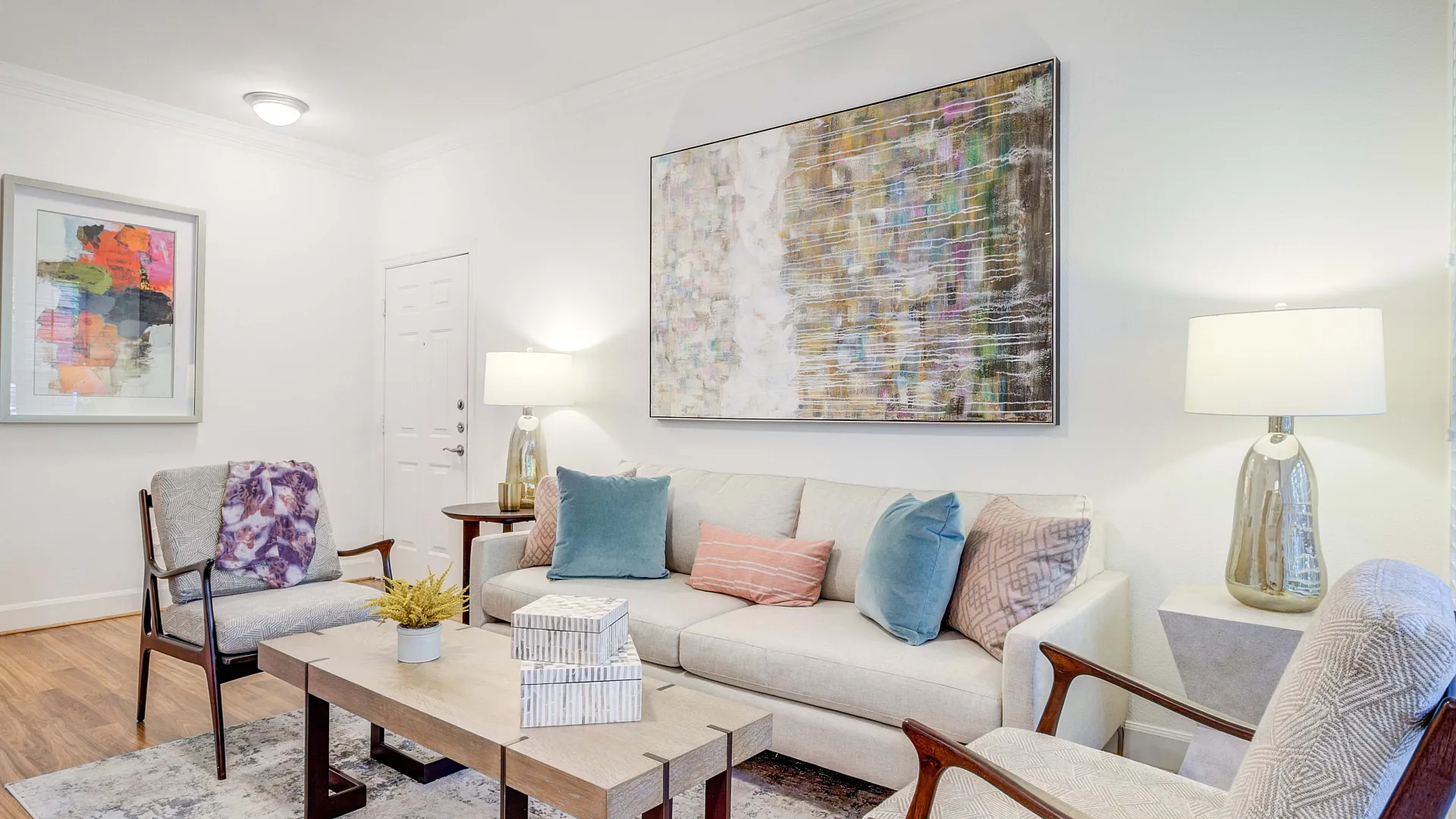 Elegant and inviting living room with stylish decor, featuring a cozy beige sofa, colorful cushions, and modern art pieces.