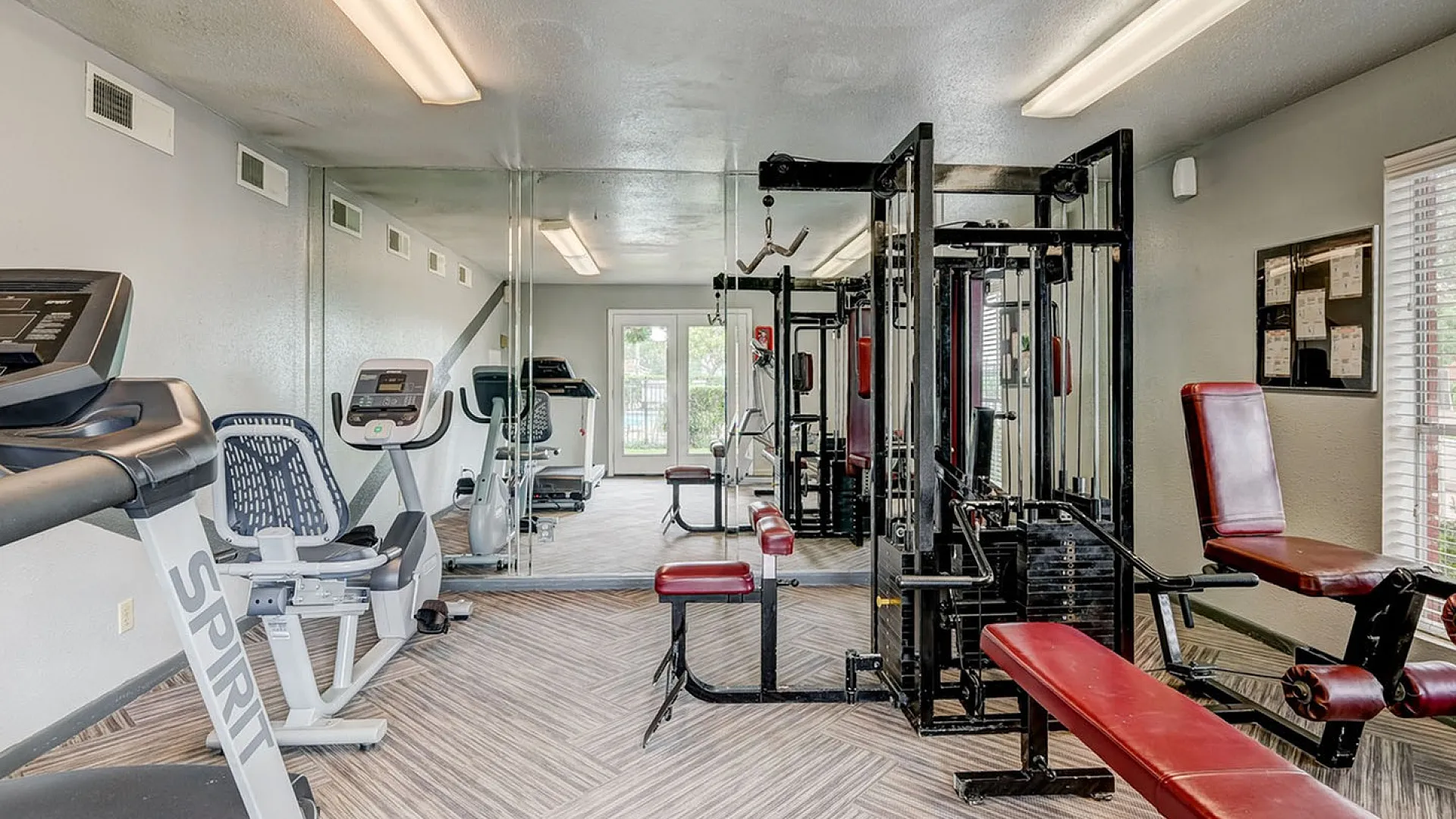 Modern fitness center featuring state-of-the-art exercise equipment, mirrored walls, and ample natural light.