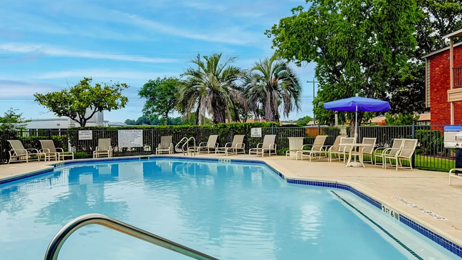 Inviting outdoor swimming pool with lounge chairs, surrounded by lush landscaping and modern apartment buildings.