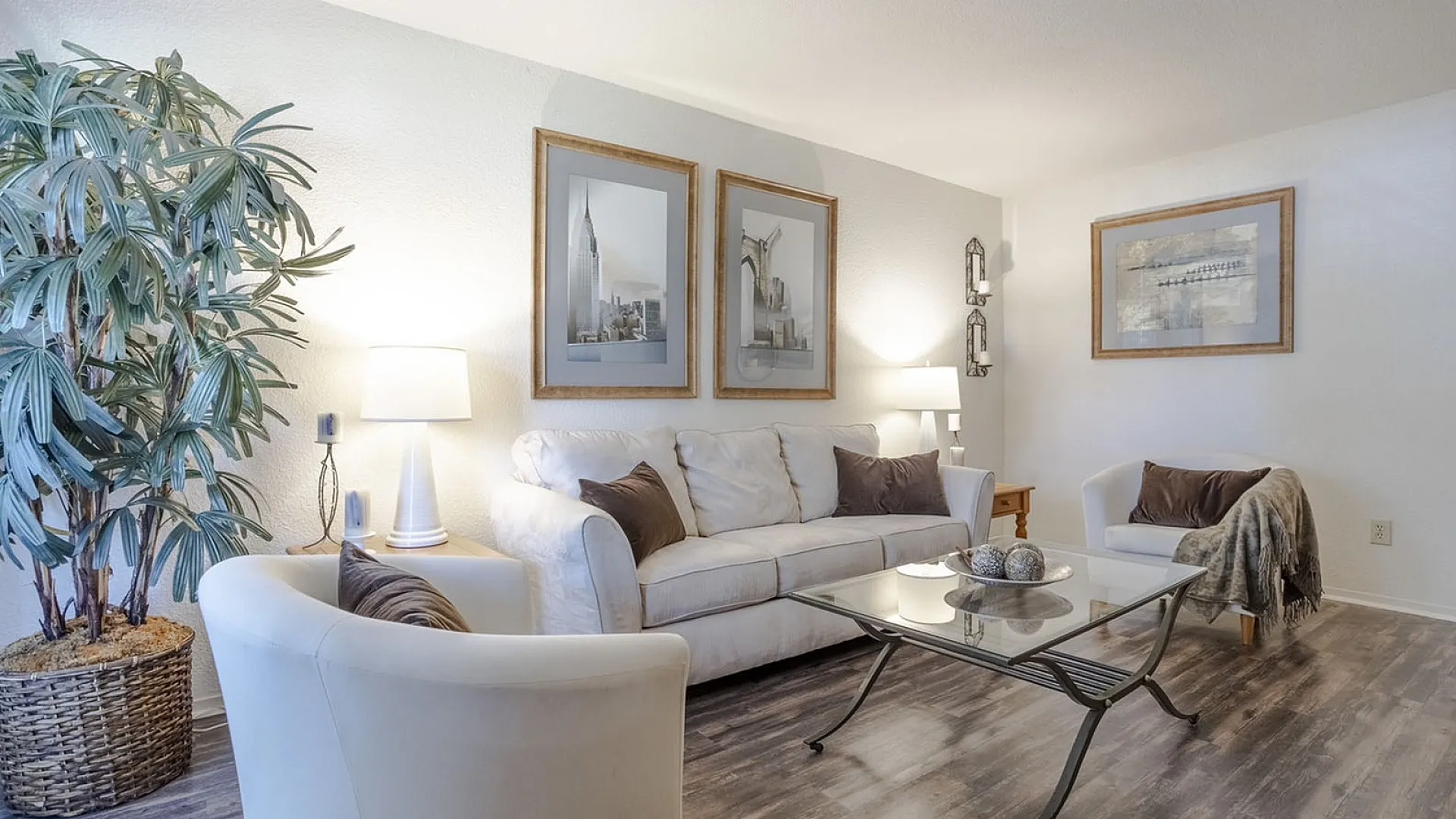 Inviting living room with elegant decor, featuring a plush white sofa, modern armchairs, and chic wall art, enhanced by soft lighting and a vibrant potted plant.