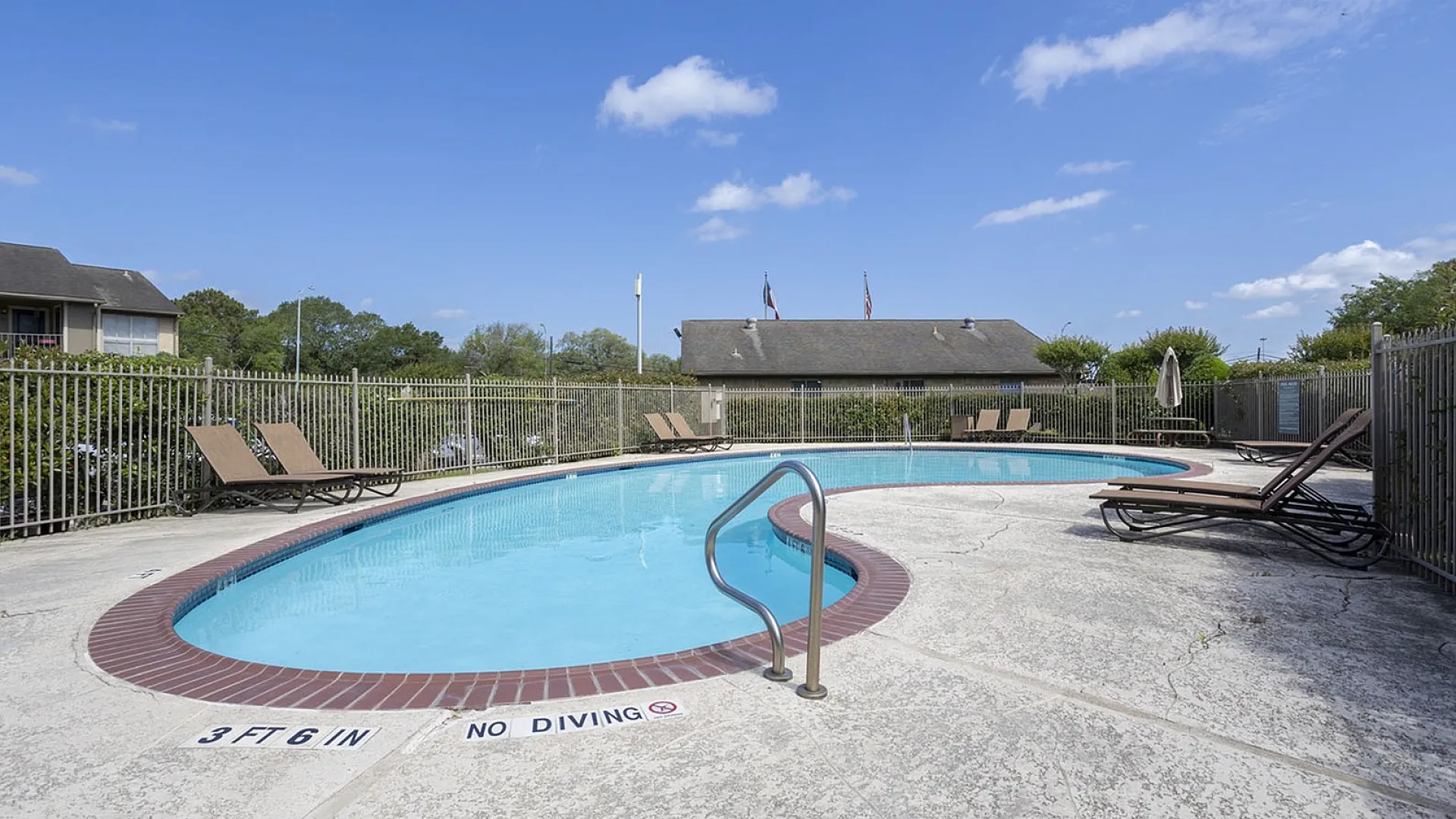Inviting outdoor pool area with sleek lounge chairs and a serene blue sky backdrop.