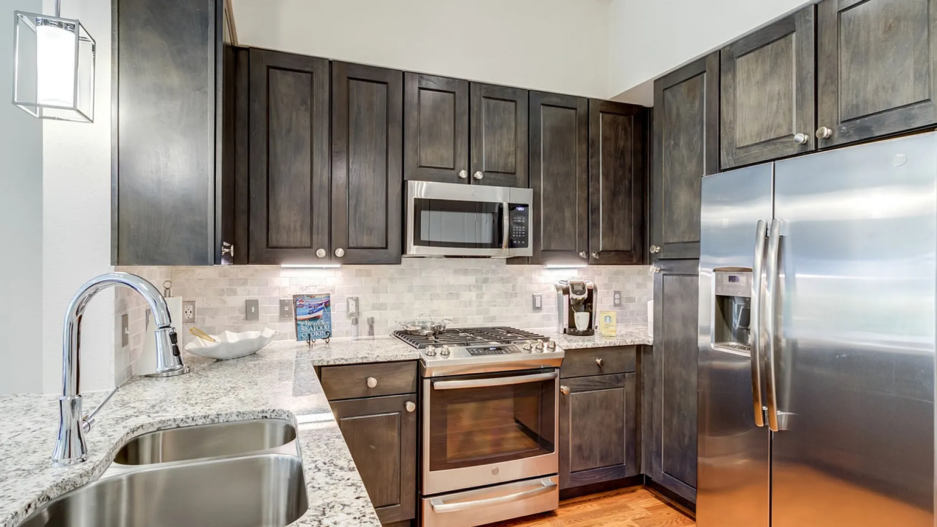 Modern kitchen featuring sleek dark wood cabinets, elegant granite countertops, and stainless steel appliances.