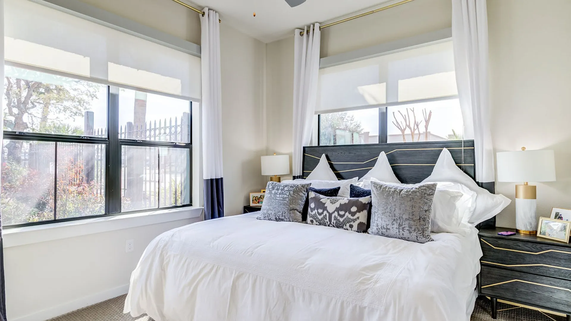 Bright and airy bedroom with elegant decor, featuring large windows, plush bedding, and chic bedside lamps.