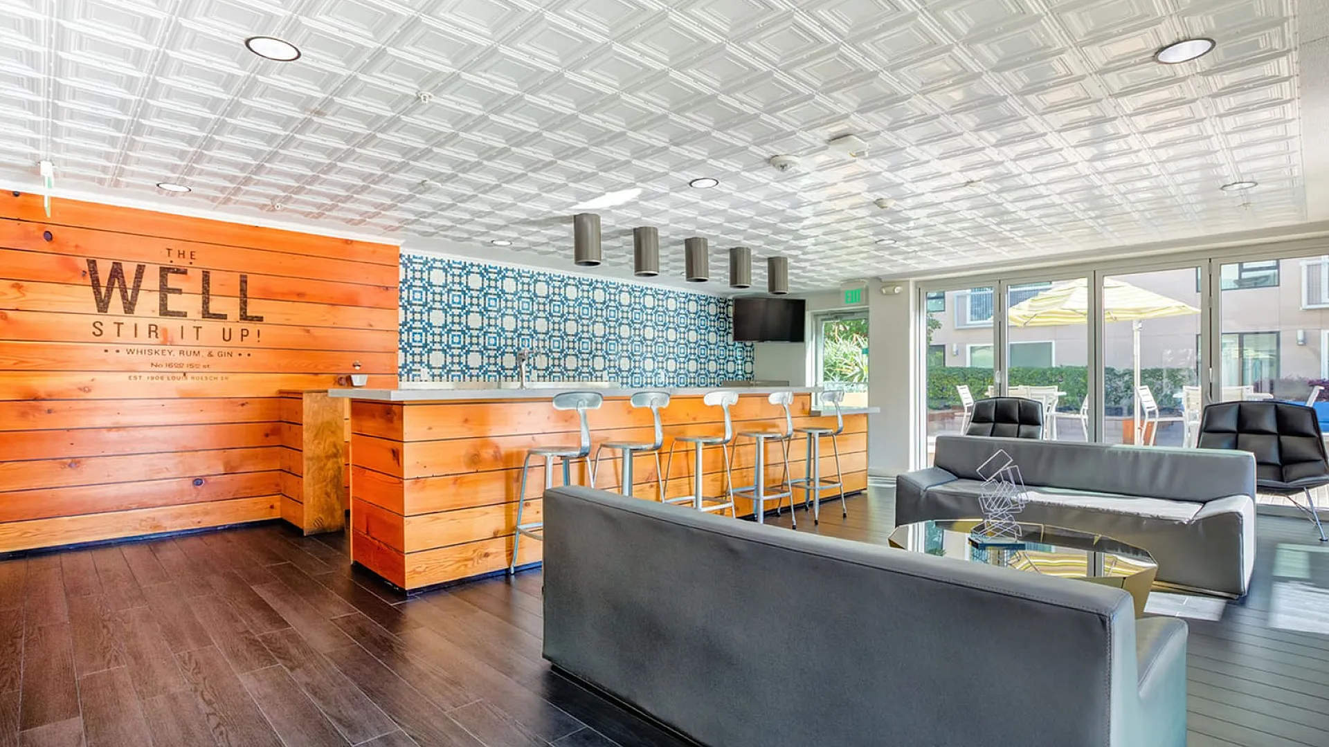 Chic lounge area with sleek bar and modern decor, featuring comfortable seating, stylish lighting, and vibrant wall art, perfect for social gatherings.