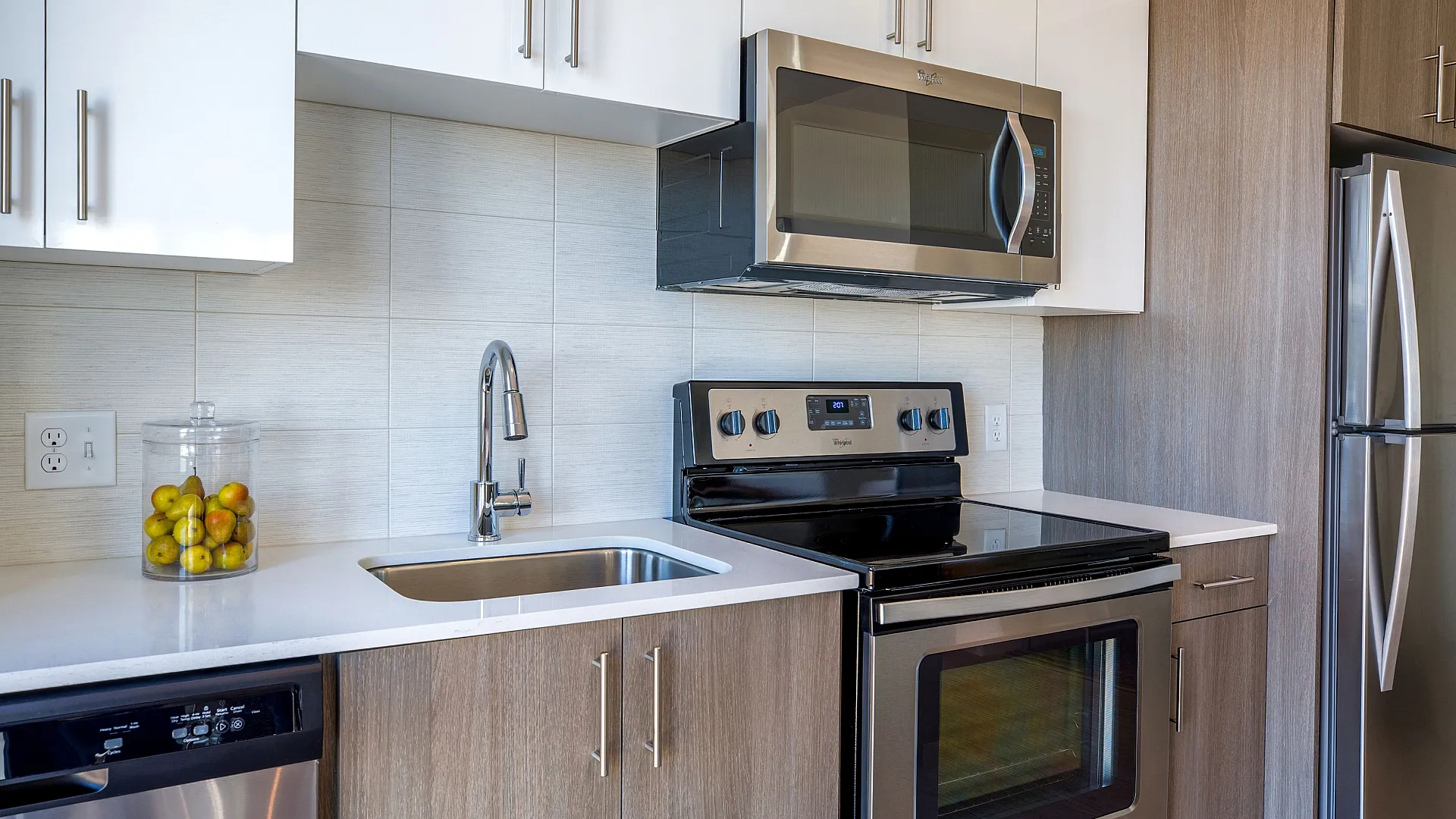 Modern kitchen with sleek stainless steel appliances, white and wood cabinetry, and a stylish sink area, perfect for culinary enthusiasts.