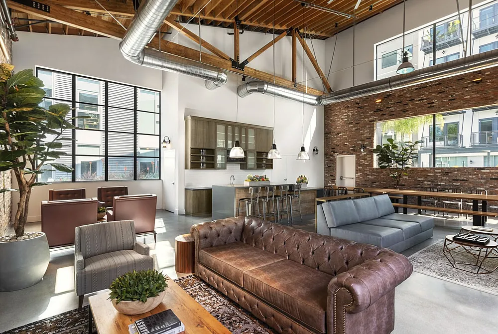 Bright and airy loft-style living area with exposed wooden beams, modern industrial design, stylish leather sofas, and a sleek open kitchen with bar seating.
