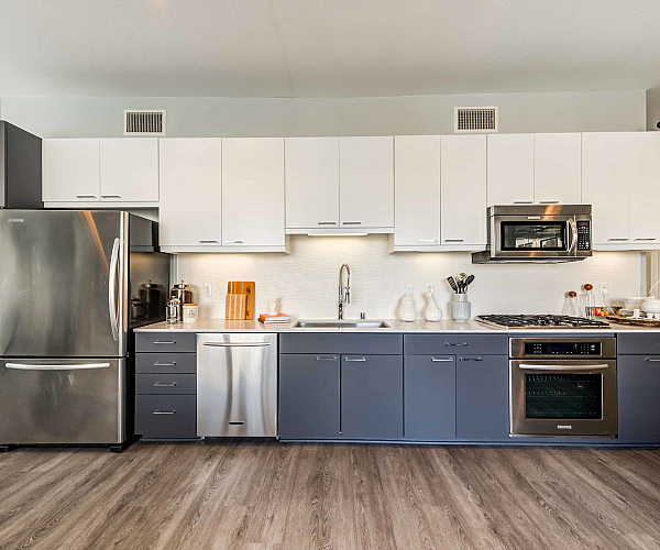 Modern kitchen with sleek stainless steel appliances, minimalist cabinetry, and elegant wood flooring.