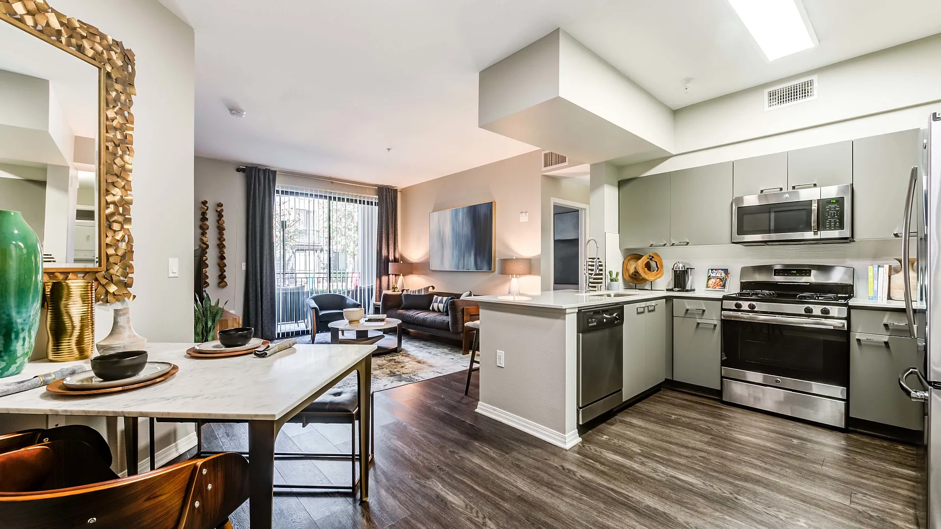 Modern open-plan kitchen and living room with stylish decor, featuring stainless steel appliances, elegant dining setup, and cozy seating area with natural light.