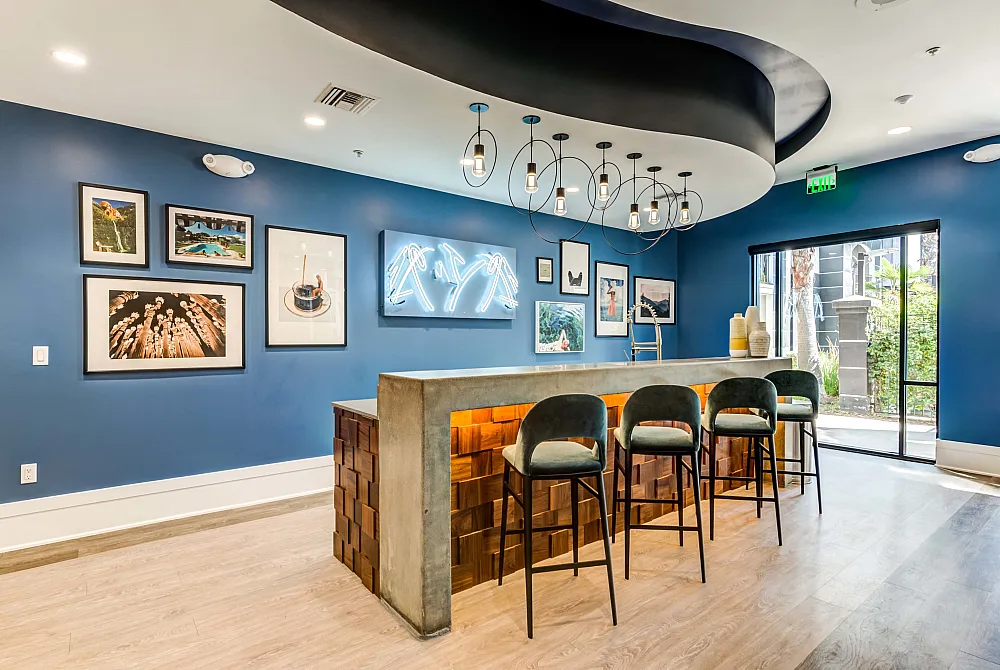 Modern and inviting lounge area with stylish bar seating, decorative lighting, and vibrant wall art, perfect for relaxation and social gatherings.