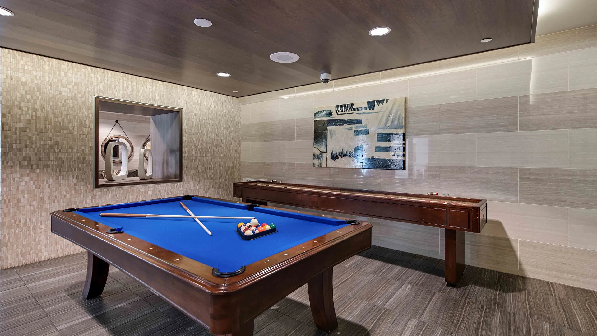 Contemporary game room featuring a sleek blue billiard table and elegant wood accents, perfect for entertainment and relaxation.