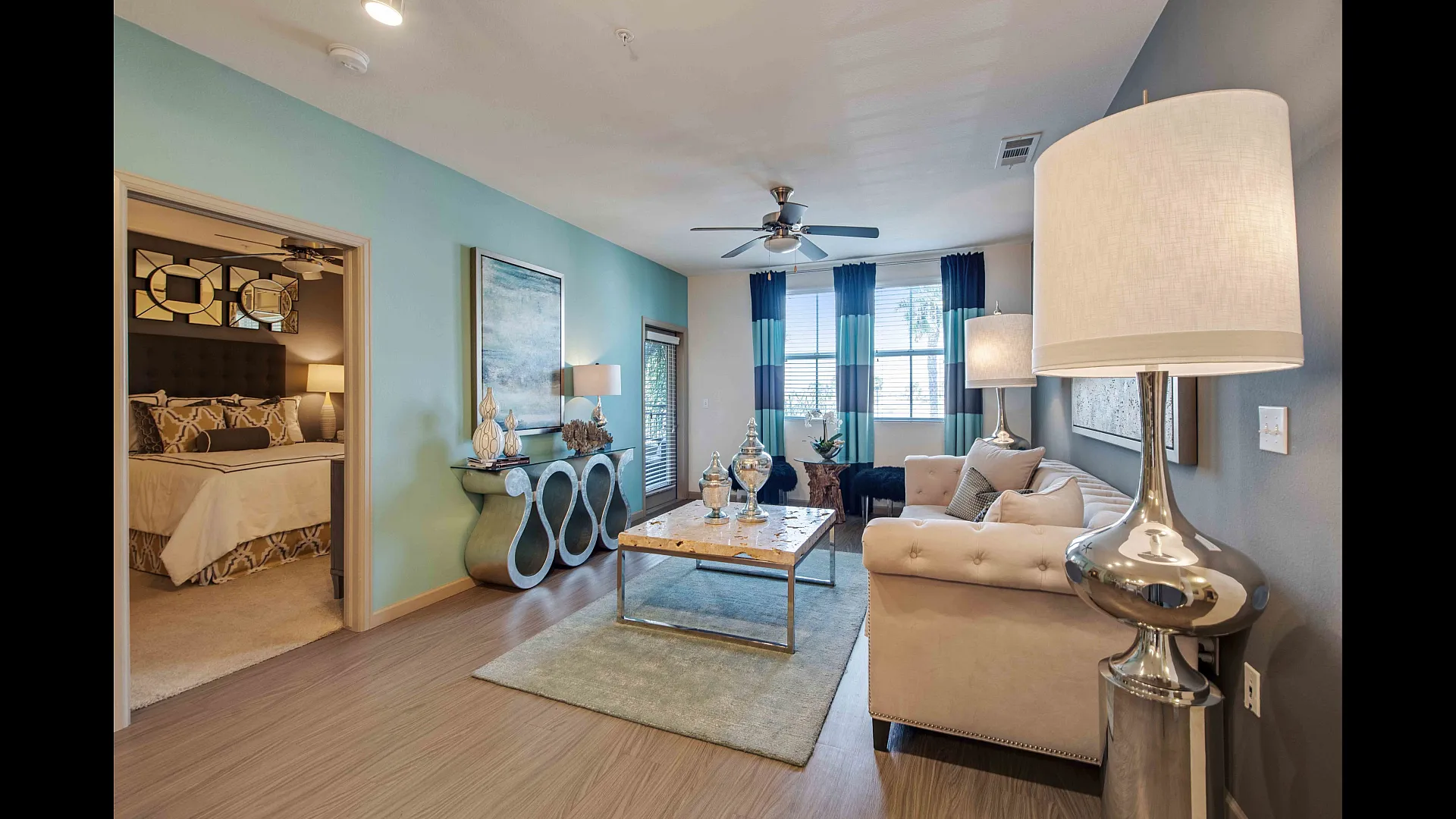 Elegant modern living room with plush furniture, stylish decor, and natural light. Inviting bedroom visible through open doorway, creating a cozy and luxurious atmosphere.