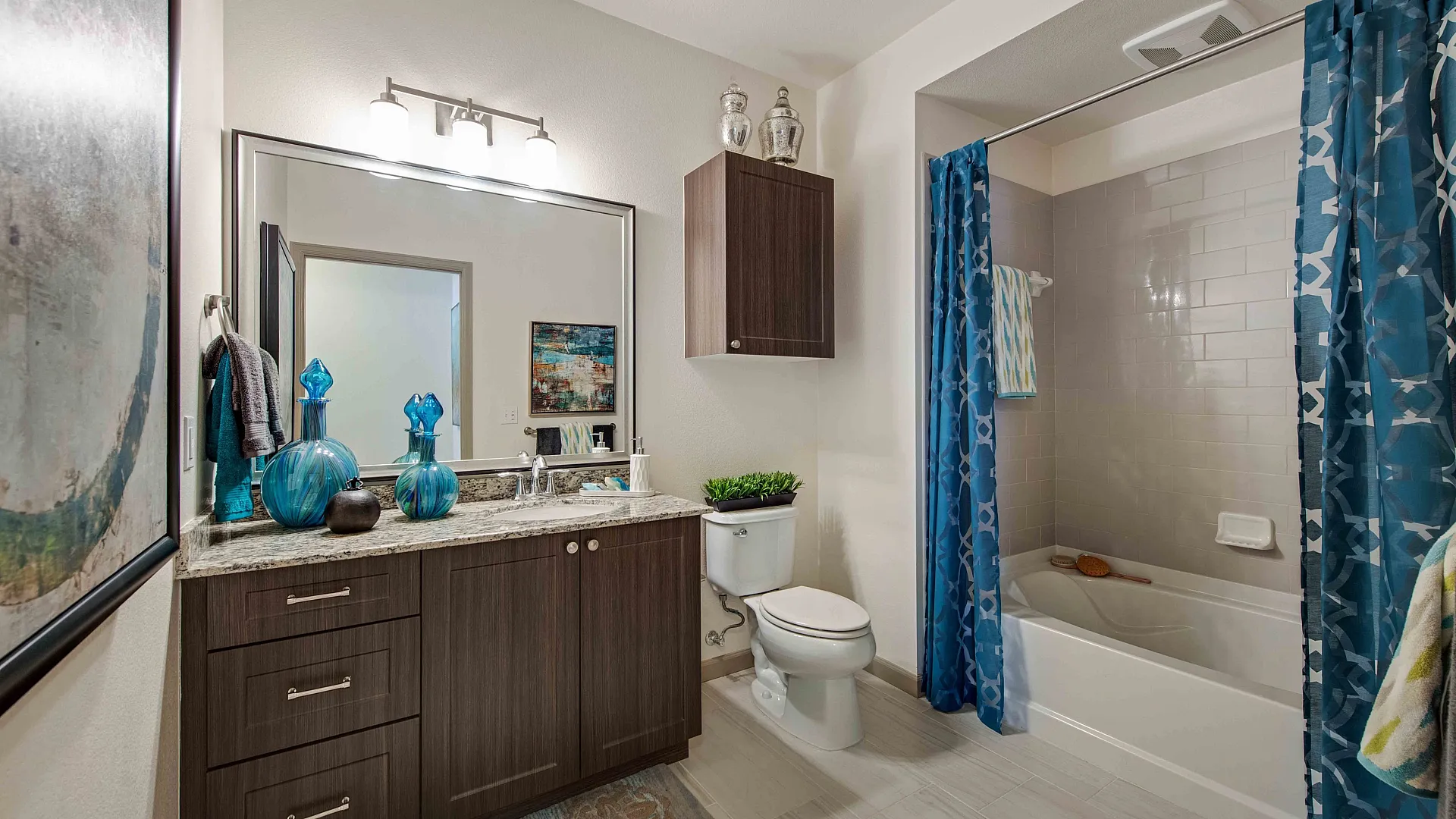Modern bathroom with elegant dark wood cabinetry, vibrant blue decor accents, and a stylish tiled shower with a patterned curtain.