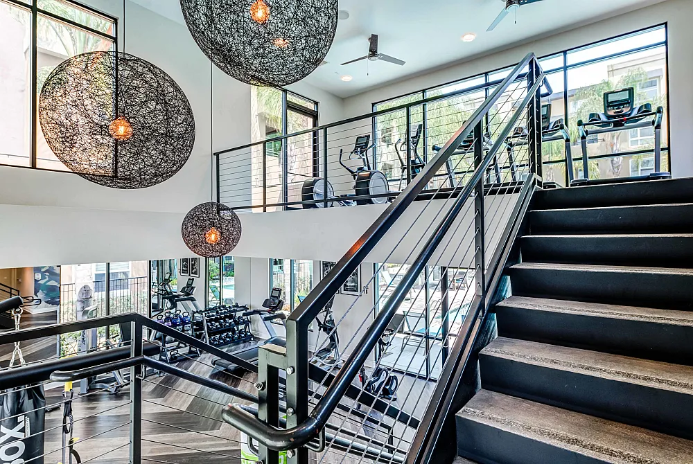 Contemporary fitness center with modern equipment, elegant lighting, and large windows offering a bright, welcoming atmosphere.