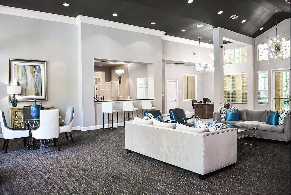 Luxurious open-concept lounge with high ceilings, elegant seating, and a chic bar area, bathed in natural light from expansive windows.
