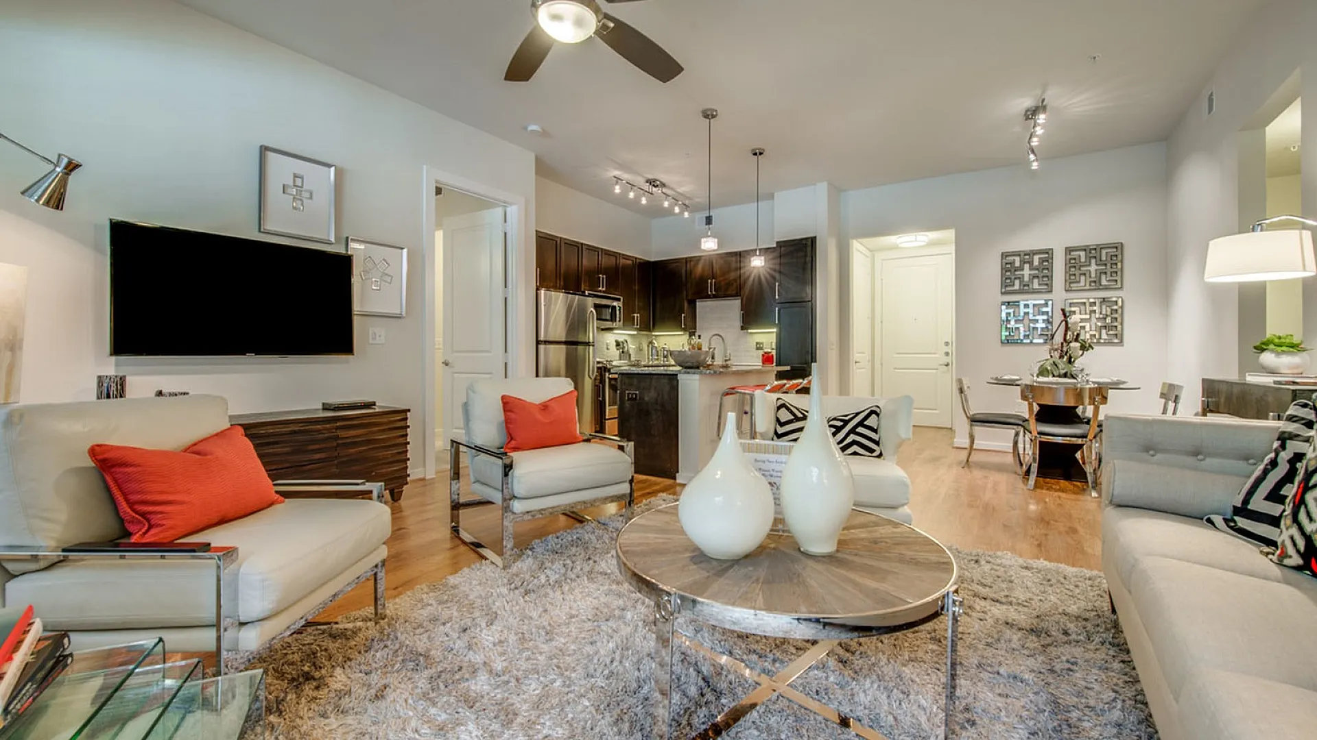 Chic modern living room with stylish furniture, vibrant accents, and an open kitchen layout, exuding elegance and warmth.