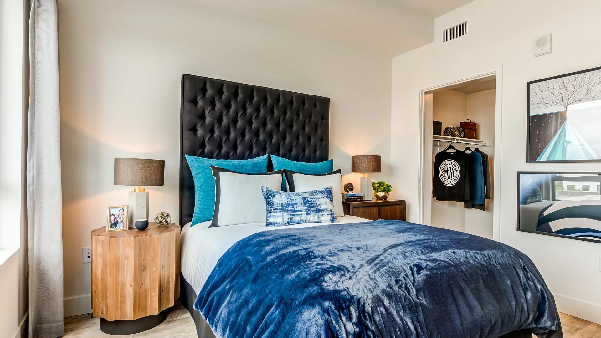 Modern bedroom with industrial ceiling, stylish decor, and cozy ambiance, featuring a plush bed, vibrant artwork, and sleek lighting.