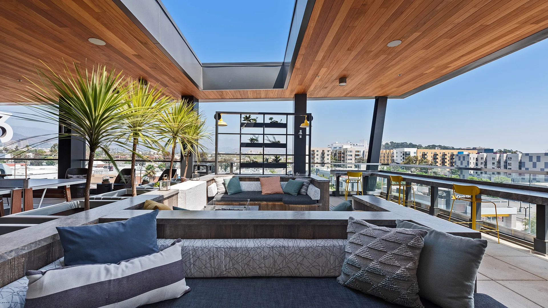 Modern fitness center with state-of-the-art cardio machines, stylish wooden ceiling, and glass walls opening to a scenic courtyard view.