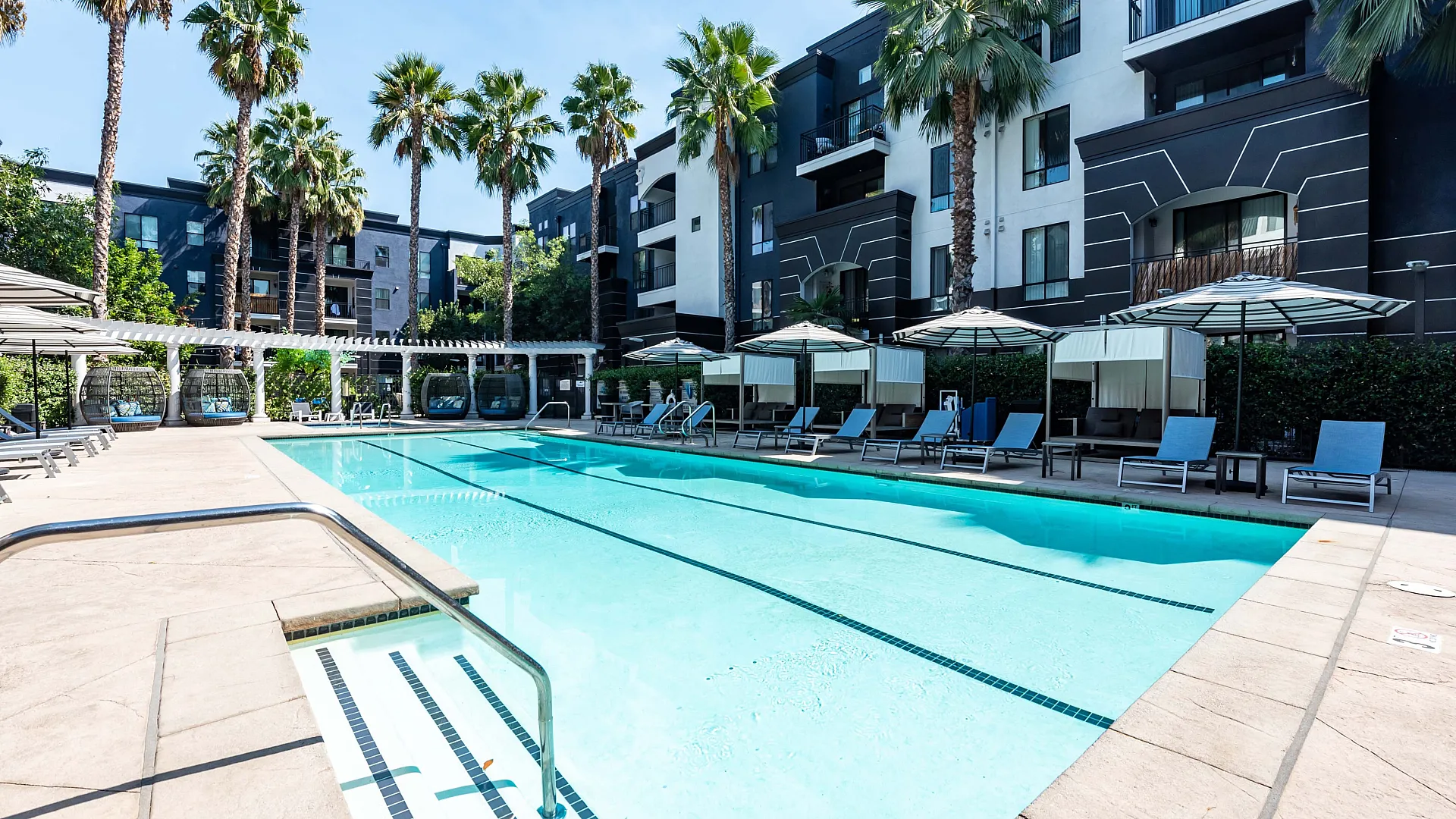 Contemporary apartment living room with elegant furnishings, stylish lighting, and large windows overlooking a scenic pool.