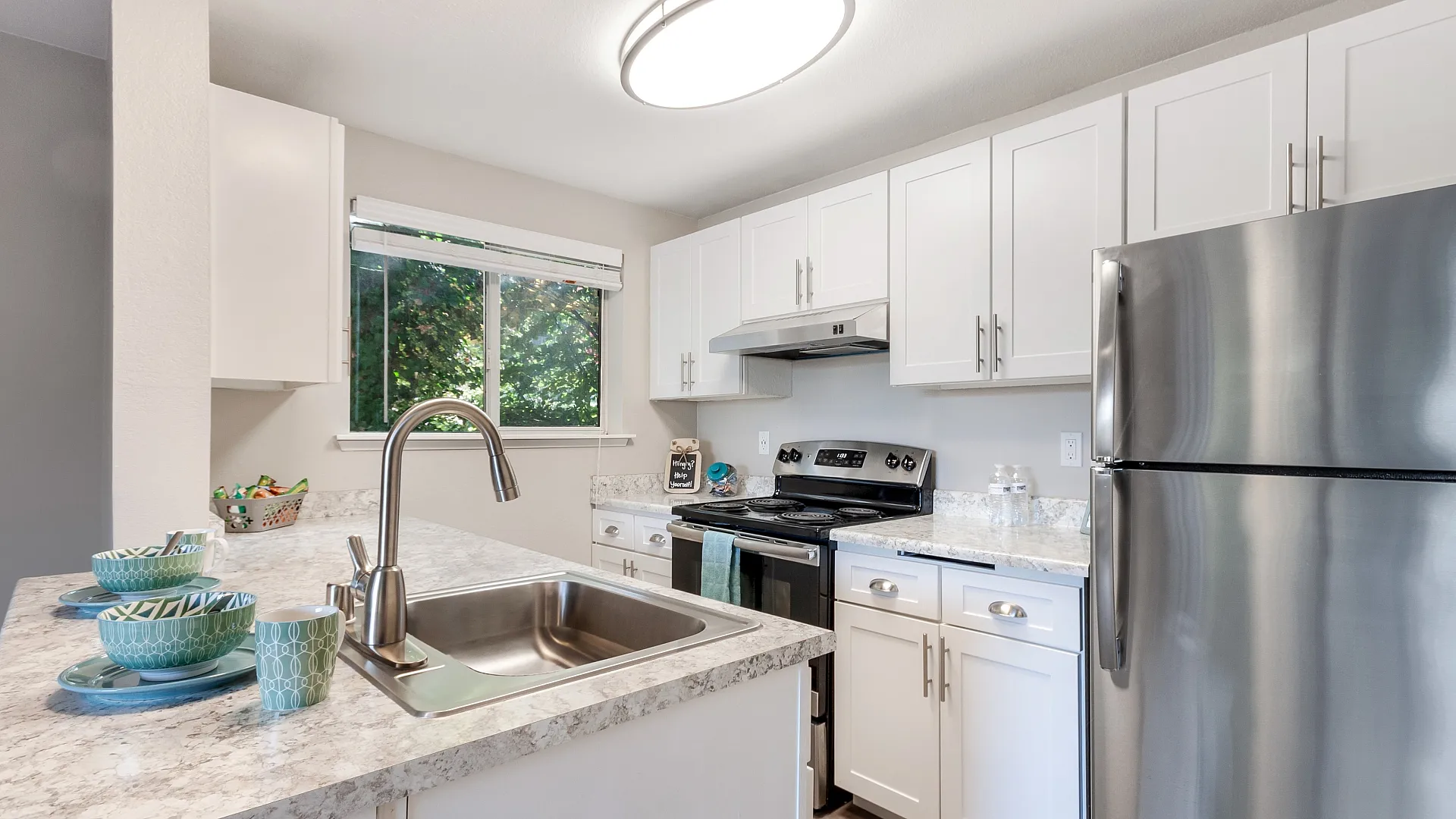 Contemporary kitchen with elegant white cabinets, stainless steel appliances, and a sleek marble countertop, creating a bright, inviting space.