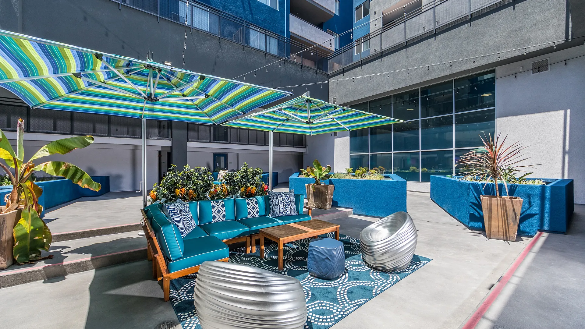 Vibrant outdoor patio featuring modern seating, colorful umbrellas, and lush planters against a stylish urban backdrop.