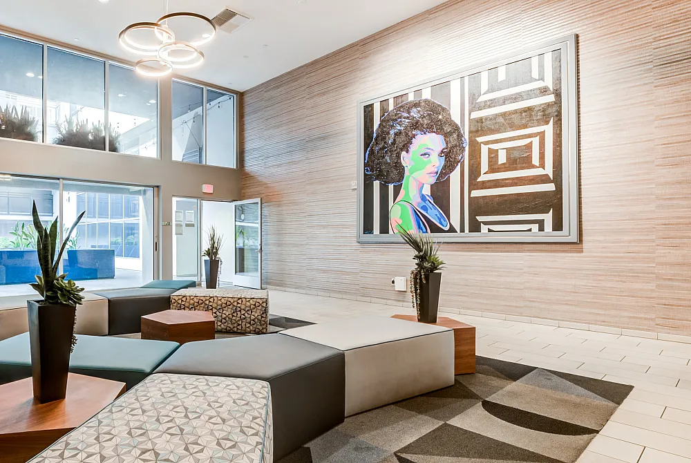 Elegant apartment lobby with modern seating, vibrant artwork, and expansive windows offering natural light.