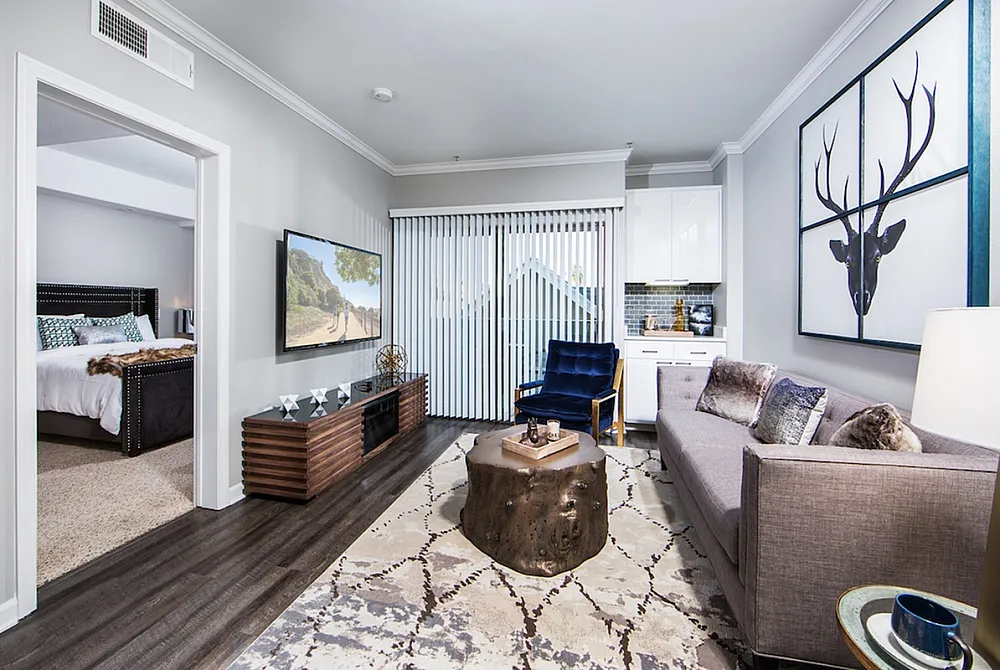 Modern apartment living room with stylish decor, featuring a cozy seating area, artistic wall art, and a glimpse of the inviting bedroom, perfect for comfortable living.