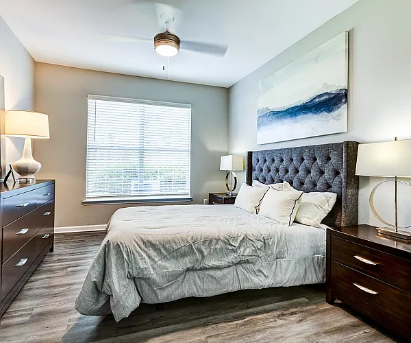 Bright and elegant bedroom with chic decor, featuring a plush bed, stylish lamps, and large window for natural light.