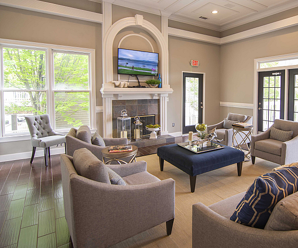 Elegant living room with plush seating and a cozy fireplace, featuring floor-to-ceiling windows and stylish decor.