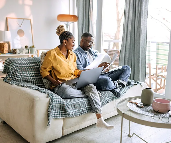 Cozy living room with a couple enjoying work from home setup, featuring bright natural light, modern decor, and a peaceful ambiance.