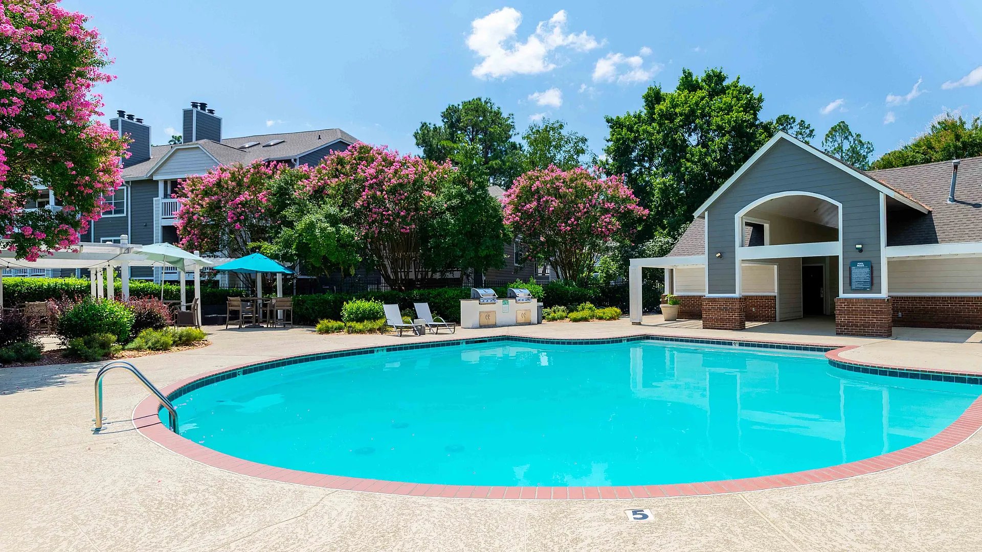 Inviting outdoor pool surrounded by lush greenery and vibrant flowers, perfect for relaxation and leisure.
