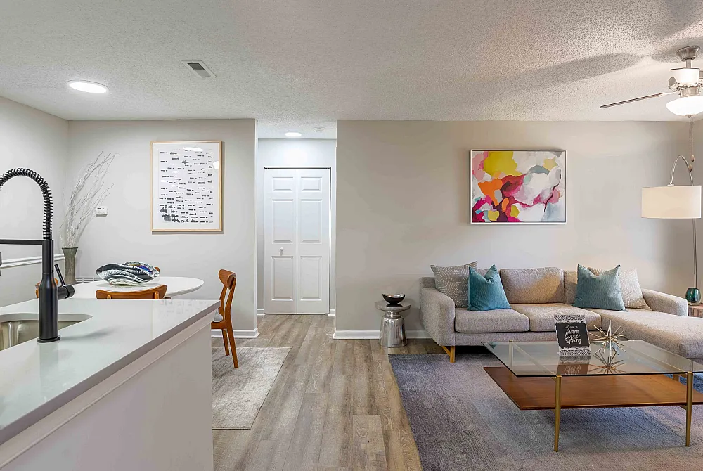 Modern apartment living area with stylish furniture, vibrant artwork, and sleek kitchen, offering a cozy and inviting atmosphere.